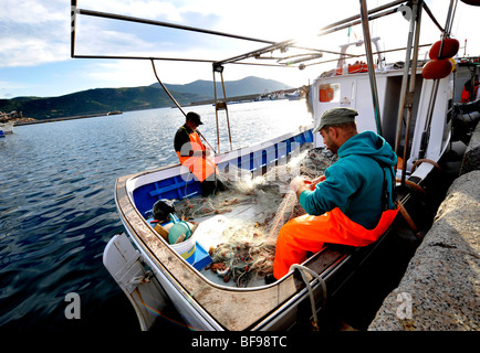 I pescatori locali sorta attraverso il pesce sulla loro barca pronta per il mercato sulla banchina a Teulada, Sud Ovest della Sardegna, Italia Foto Stock