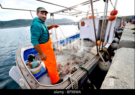 Un pescatore locale ordina attraverso il suo pesce sulla sua barca pronta per il mercato sulla banchina a Teulada, Sud Ovest della Sardegna, Italia Foto Stock