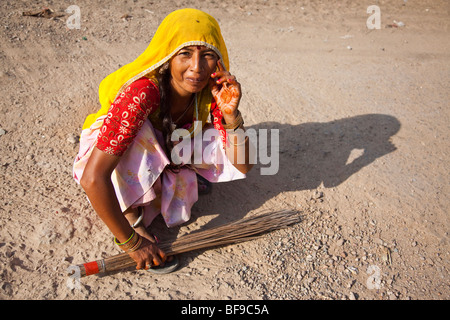 Donna spazzare una strada sterrata a Pushkar Mela in Pushkar nel Rajasthan in India Foto Stock