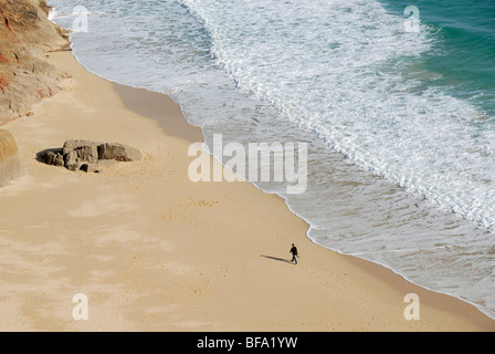 Figura solitaria camminando lungo la spiaggia, Cornwall, England, Regno Unito Foto Stock