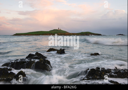 Acque vorticose come le onde rompono sul primo piano di Ballycotton Bay, Co.Cork, Irlanda,con Ballycotton faro in background Foto Stock