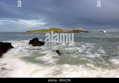 Acque vorticose come le onde rompono sul primo piano di Ballycotton Bay, Co.Cork, Irlanda,con Ballycotton faro in background Foto Stock