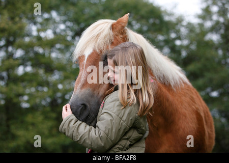 Cavalli domestici (Equus przewalskii f. caballus), ragazza caressfully abbracciando la testa di un cavallo, Germania Foto Stock