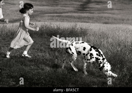 Un ragazzo e una ragazza che corre su Primrose Hill con un cane dalmata. Il cane ha un sorriso sornione espressione come nel cartoon Foto Stock