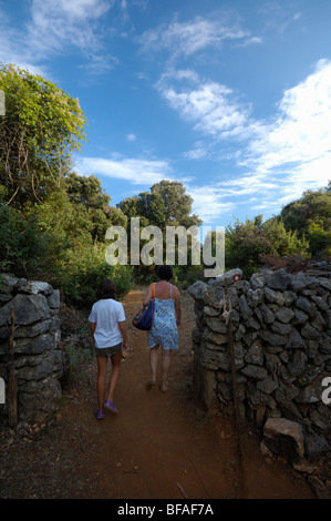 Isola di Cres, Croazia, madre e figlia che passa attraverso il gateway a secco di muro di pietra Foto Stock