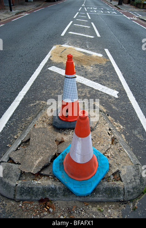 Due coni di traffico segnando un danneggiamento del tratto di strada a Teddington, Middlesex, Inghilterra Foto Stock