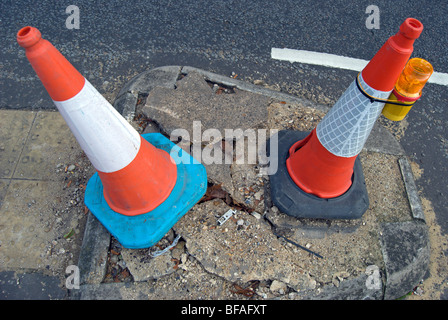 Due coni di traffico segnando un danneggiamento del tratto di strada a Teddington, Middlesex, Inghilterra Foto Stock