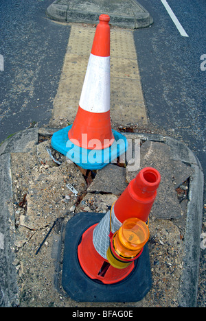 Due coni di traffico segnando un danneggiamento del tratto di strada a Teddington, Middlesex, Inghilterra Foto Stock