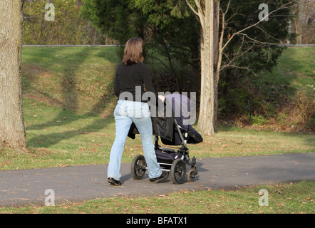 Una giovane madre a piedi il suo bambino nel parco. Foto Stock