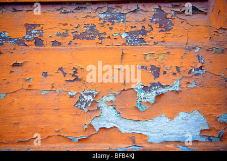 Primo piano di peeling vernice arancione su una parete Foto Stock