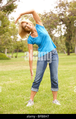 Senior donna esercita in posizione di parcheggio Foto Stock