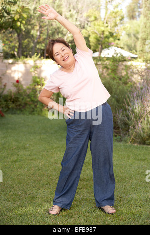 Senior donna esercita in giardino Foto Stock