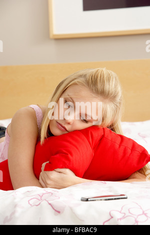 Triste ragazza adolescente in camera da letto con telefono mobile Foto Stock