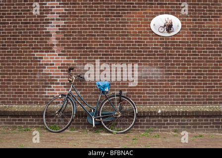 Bicicletta contro un muro di mattoni decorata con una foto di famiglia, Amsterdam, Olanda Foto Stock