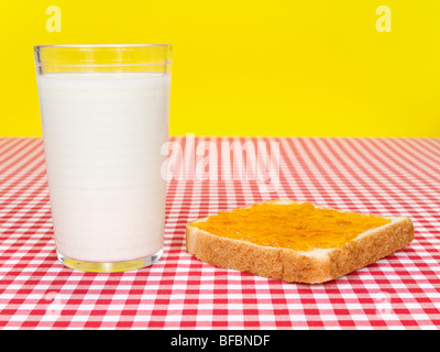 Un bicchiere di latte e una diffusione di toast con marmellata al di sopra della tabella. Foto Stock