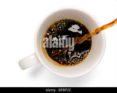 Il caffè fresco che viene versato in una tazza di caffè su uno sfondo bianco. Foto Stock