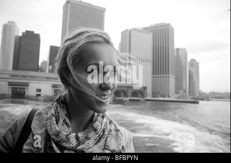 Donna bionda su Staten Island Ferry, New York City in background Foto Stock