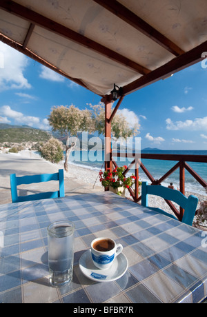 Caffè greco e glas pieno di acqua su un tavolo in una taverna in una zona appartata e serena beach in Grecia. Foto Stock