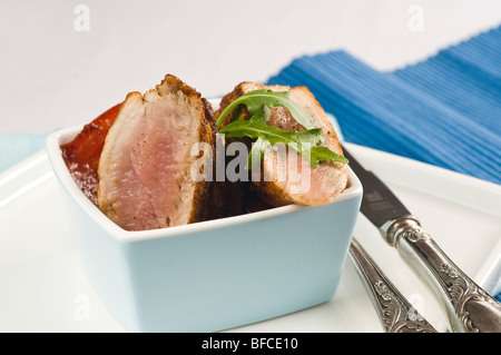 La carne di maiale fritto in una luce blu ciotola con erbe aromatiche Foto Stock