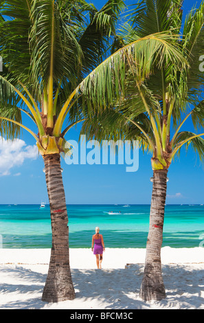 Donna che cammina verso il mare tra due palme Boracay; Il Visayas; Filippine. Foto Stock