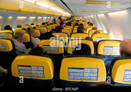 I sedili e i passeggeri seduti durante un volo a bordo di un aeromobile di Ryanair visto dall'emergenza backshowing procedura avviso Foto Stock