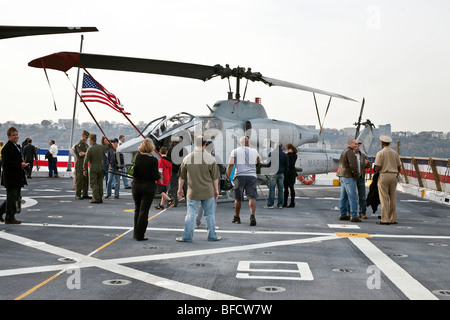 I visitatori si radunano intorno Marine elicottero Cobra & i suoi piloti sul ponte di volo della USS New York ormeggiata presso il Molo 88 in New York Foto Stock