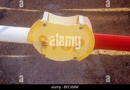 Rosso e bianco barriera del veicolo su strada con strisce di luce del sole e con una rotta split sbiadito e segno di plastica indicando Stop Foto Stock