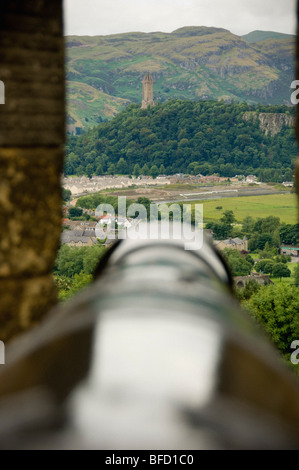 Cannone sulle merlature del Castello di Stirling, con il monumento Wallace in cima all'Abbazia Craig e il Parco Nazionale Trossachs in lontananza. Scozia. Foto Stock