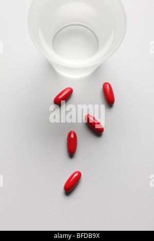 Pills accanto a un bicchiere di acqua Foto Stock