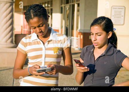 Appendere appendere fuori americano africano e ispanica ragazze teenager sms sul cellulare signor ©Myrleen Pearson Foto Stock