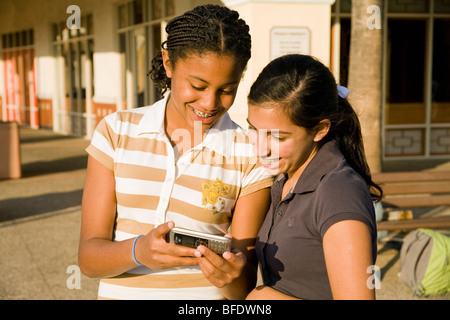 Appendere appendere fuori insieme americano africano e ispanica ragazze teenager sms sul cellulare signor ©Myrleen Pearson Foto Stock