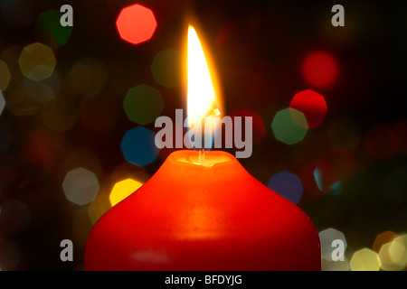 Red christmas candle burning acceso nella parte anteriore di un albero di natale Foto Stock