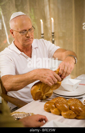 L'uomo la benedizione sul pane challah in una festosa cena di famiglia. Foto Stock