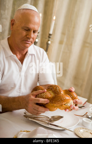 L'uomo la benedizione sul pane challah in una festosa cena di famiglia. Foto Stock