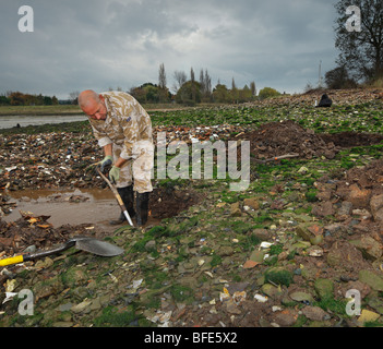 L uomo lo scavo per bottiglie di antiquariato in un dump di stile vittoriano. Abbassare Halstow, Kent, Inghilterra, Regno Unito. Foto Stock