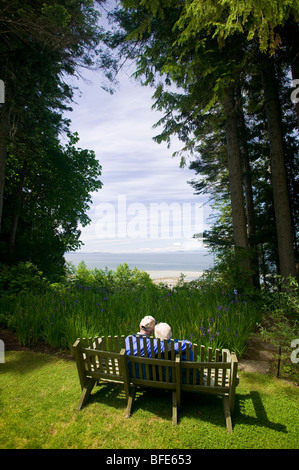 Una coppia senior seduta su una panchina, Qualicum Beach, l'isola di Vancouver, British Columbia, Canada Foto Stock