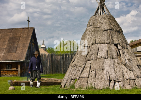 Carattere in costume accanto a un teepee nel Sainte-Marie tra gli Hurons insediamento nella città di Midland, Ontario, Canada Foto Stock