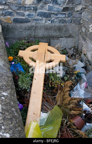 Essendo stato sostituito da una lapide in pietra temporaneamente una croce di legno in stile celtico è scartato in un cimitero irlandese Foto Stock