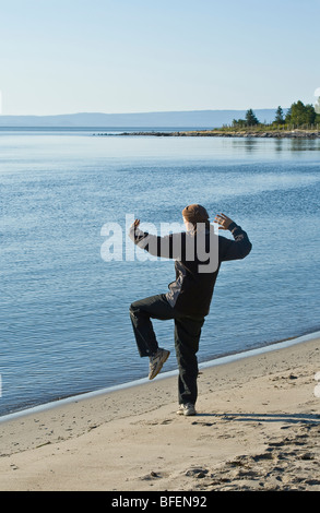 Persona praticare il Tai-chi di mattina presto su Cap-aux-Oies beach in Charlevoix, Quebec, Canada Foto Stock