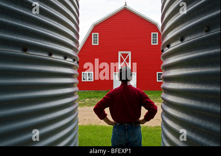 Primo piano dei contenitori del cereale con l uomo e granaio rosso sullo sfondo vicino a Torquay, Saskatchewan, Canada Foto Stock