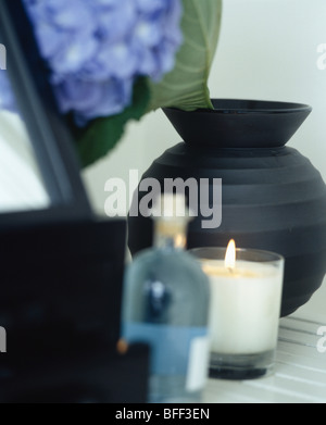 Close-up del cero acceso in un barattolo di vetro accanto al vaso nero e blu bottiglia di vetro Foto Stock