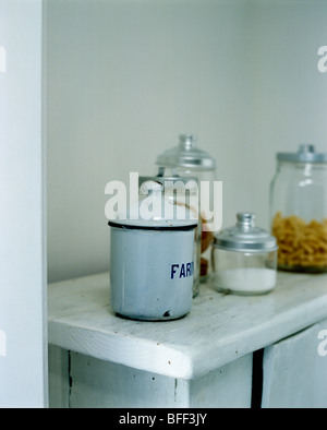 Close-up di smaltato bianco francese stagno di archiviazione sul piano di lavoro in marmo con metallo-lidded vetro vasetti di storage Foto Stock