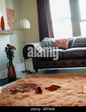 Divano in pelle nera e arancione pelliccia sintetica Tappeto nel soggiorno moderno Foto Stock