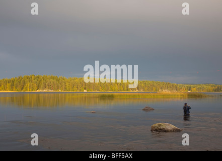 Pesca a mosca in un piccolo fiume e lago, Finlandia Foto Stock