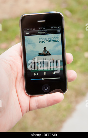 Un uomo di utilizzare l'applicazione MP3 su un Apple iPhone. Foto Stock