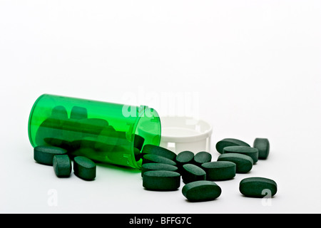 Prescrizione verde bottiglia rovesciato con le pillole di verde e di un tappo di plastica Foto Stock