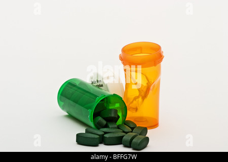 La plastica fusa bottiglia di prescrizione accanto alla capsula di chiusura in plastica bianca con una prescrizione verde bottiglia rovesciato con le pillole di verde Foto Stock