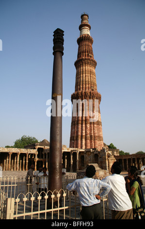 Tre locali indiani guardare il misterioso antiruggine colonna di ferro nel Qutb () Qutub Minar complesso, Delhi Foto Stock