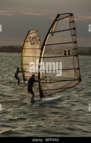 Gli appassionati di windsurf al tramonto sul serbatoio Farmoor, Oxfordshire, Regno Unito Foto Stock