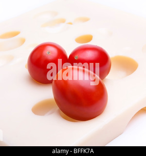 Close up di cherry plum pomodori sullo sfondo del formaggio svizzero. Foto Stock